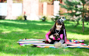 Маленькая девочка с котом сидит на зеленой траве