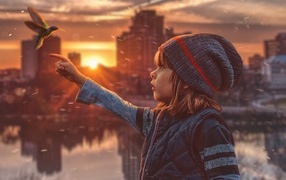 Маленькая девочка с птицей колибри на фоне города