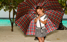 Маленькая девочка с большим зонтом на пляже