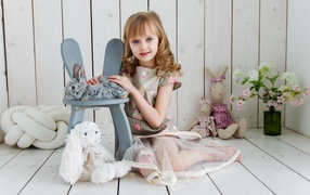 Маленькая девочка с игрушками в комнате сидит на полу