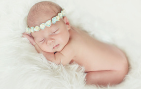 Маленький спящий ребенок на меховом покрывале