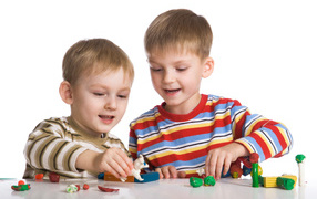 Два мальчика играют в игрушки на белом фоне