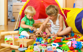 Два маленьких мальчика играют с игрушками на полу