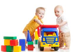 Два маленьких ребенка с игрушками на белом фоне