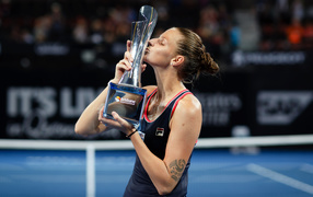 Чешская теннисистка Каролина Плишкова целует кубок на корте
