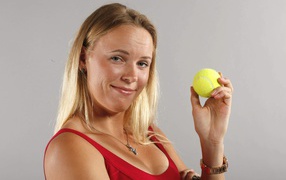 Danish tennis player Caroline Wozniacki with a ball in her hand on a gray background