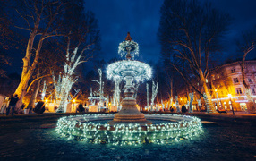 Beautiful fountain with garlands in the city in the evening