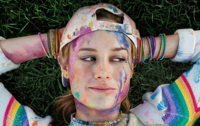 Actress Brie Larson with a face in the paint lies on the grass