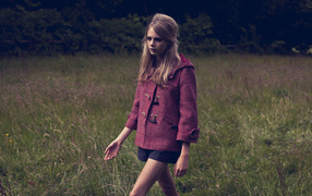 Actress Cara Delevingne walking through the grass in a coat