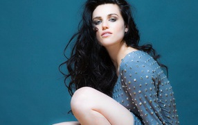 Actress Katie McGrath in a gray dress on a blue background