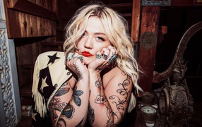 Голубоглазая блондинка с татуировками на руках