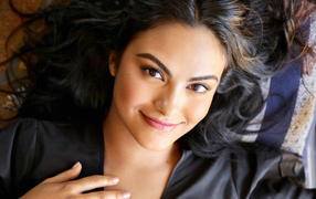 Brown-eyed actress Camila Mendes lies on the bed