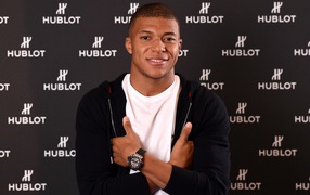 Football player Kilian Mbappa in a suit with a clock on his hand