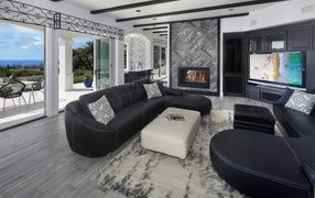 Большая просторная гостиная с черными кожаными диванами, телевизором и камином 