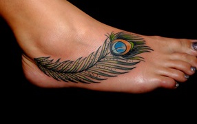 Татуировка перо павлина на ноге на черном фоне