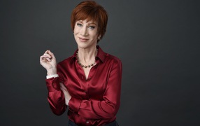 Red-haired actress Kathy Griffin in a red shirt on a gray background