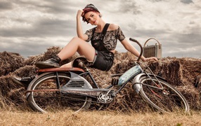 Девушка ретро сидит на сене с велосипедом