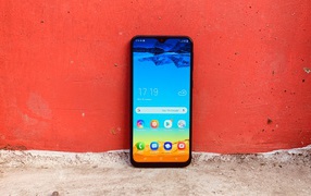 Смартфон Samsung Galaxy M20 у красной стены