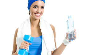 Sports girl with dumbbells with a bottle of water in her hand