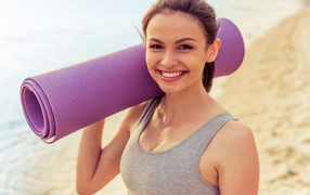 Sports girl with yoga mat on the beach