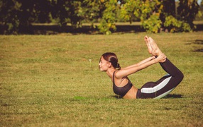 Девушка занимается гимнастикой на зеленой траве