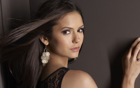 Ветер развивает волосы актрисы Нина Добрев на фоне стены