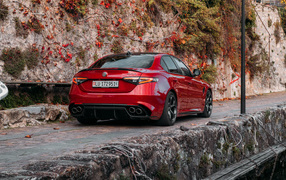 Красный автомобиль Alfa Romeo Giulia Quadrifoglio 2021  года на дороге в горах