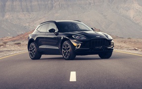 Черный автомобиль aston Martin DBX 2020 года на трассе в горах