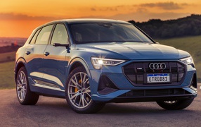 Синий автомобиль Audi E-Tron 55 Quattro S Line 2020 года на закате