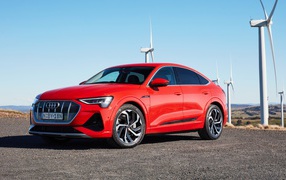 Red car Audi E-Tron 50 Quattro Sportback S Line 2020 against the background of wind turbines
