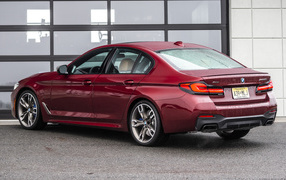 Красный автомобиль BMW M550i XDrive, 2021 года вид сзади
