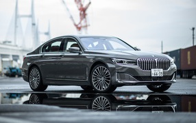Серебристый автомобиль BMW 745e на мокром асфальте 