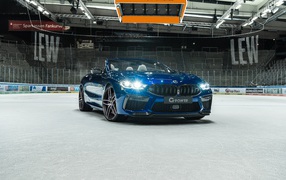 Кабриолет BMW M8,  2020 года с включенными фарами на стадионе 
