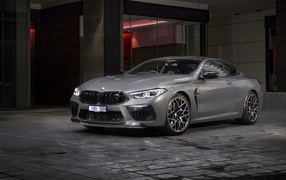 Серебристый автомобиль BMW M8 Competition Coupe 2020 года у здания 