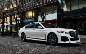Белый автомобиль  BMW 740i M Sport 2020 года у кафе