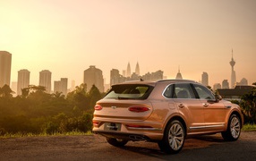 Автомобиль Bentley Bentayga V8 2020 года вид сзади на фоне города 