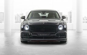 Черный автомобиль Mansory Bentley Flying Spur 2020 года с включенными фарами 