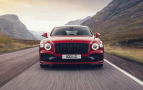 Красный автомобиль Bentley Flying Spur V8 2020 года на дороге в горах 
