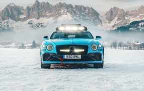 2020 blue car Bentley Continental GT Ice Race on a background of snow-capped mountains