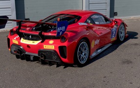 Красный спортивный Ferrari 488 Challenge Evo 2020 года у гаража 