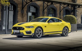 Желтый автомобиль Ford Mustang Mach 1 2021 года у здания