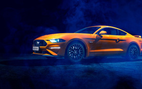 Оранжевый автомобиль Ford Mustang в дыму
