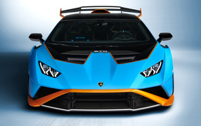 Голубой автомобиль Lamborghini Huracán STO 2021 года вид спереди на сером фоне