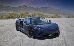 Черный автомобиль  McLaren GT, 2020 года под звездным небом