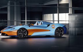 Спортивный автомобиль McLaren Elva Gulf Theme By MSO 2021 года у стеклянной стены 