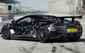 Черный спортивный автомобиль McLaren 620R на автодроме