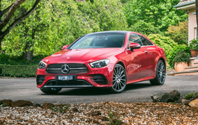 Красный автомобиль Mercedes-Benz E 300 AMG, 2020 года у дома осенью