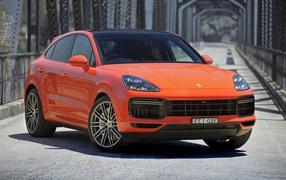 Оранжевый внедорожник Porsche Cayenne Turbo Coupe 2019 года на мосту