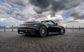 Черный автомобиль Porsche 911 Carrera 4S Cabriolet 2020 года под грозовым небом