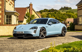 Голубой автомобиль Porsche Taycan 4S 2021 года у дома вид спереди